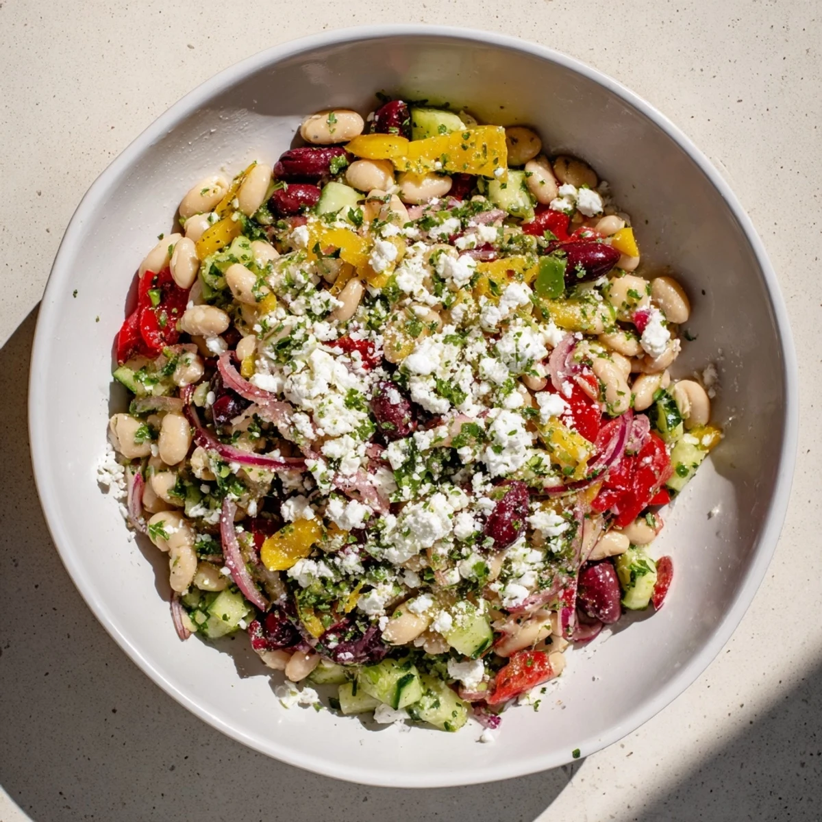A close-up of a bowl shows the bright, flavorful Mediterranean white bean salad just ready.