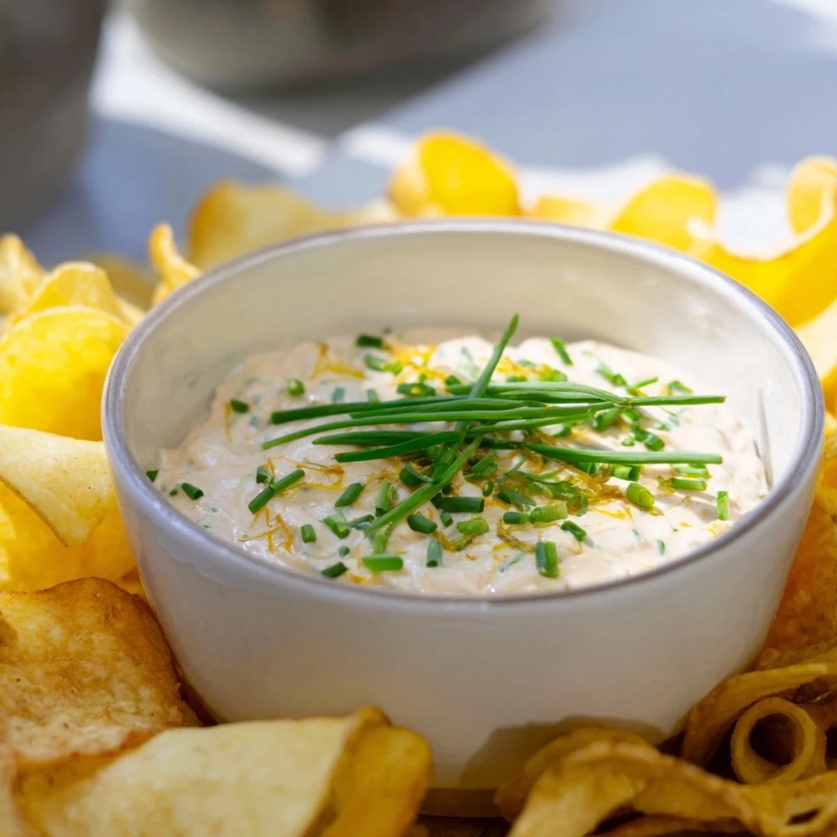 Delicious, creamy onion dip with fresh chives, ready to be scooped up with potato chips.