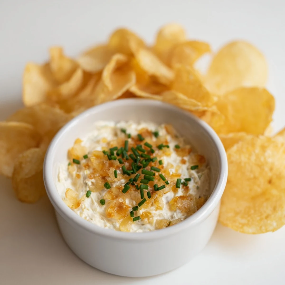 Crisp golden potato chips served alongside a creamy, flavorful onion dip, a classic snack.