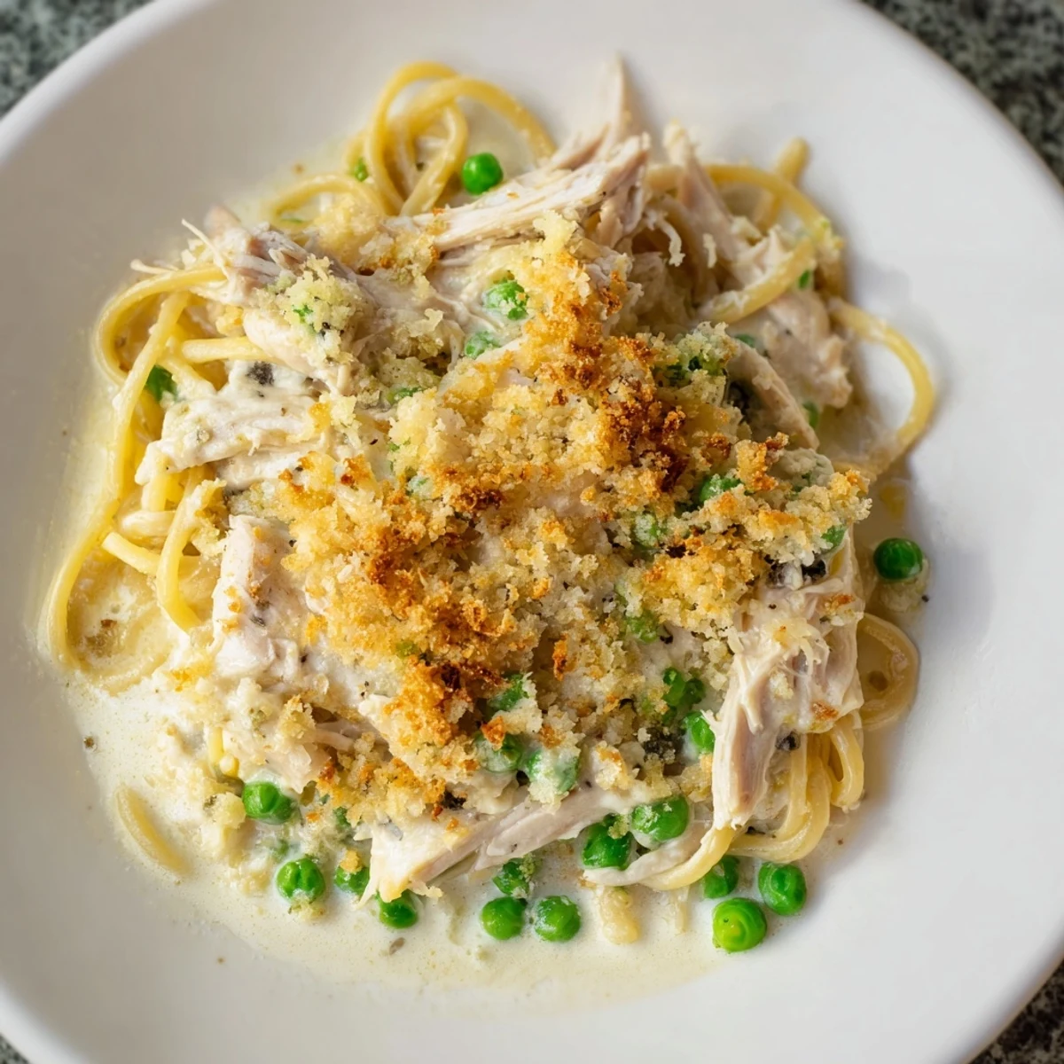 Golden-crusted Turkey Tetrazzini bake, a creamy pasta dish with tender turkey and sweet peas.