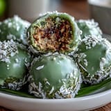 Vibrant matcha coconut energy balls with oats, rolled in shredded coconut for a healthy, energizing snack.