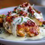 Creamy Tuscan Chicken with Sun-Dried Tomatoes in a skillet, golden-seared chicken breasts in a rich, creamy sauce with spinach and basil.