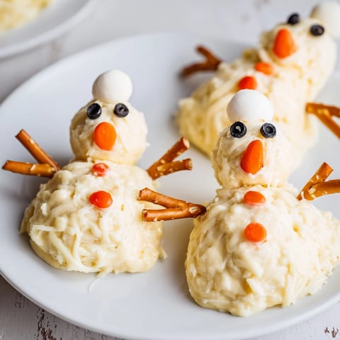 Melted Snowman Cheese Bites: a creamy, cheesy appetizer with black olive eyes and pretzel arms.