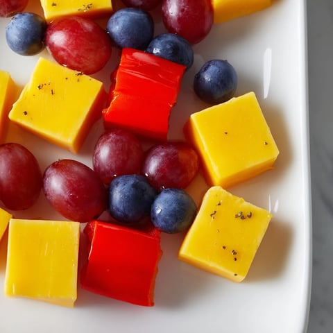 Bright, geometric Bauhaus Block appetizer showcasing vivid bell peppers, cheese, and grapes, ready to serve.