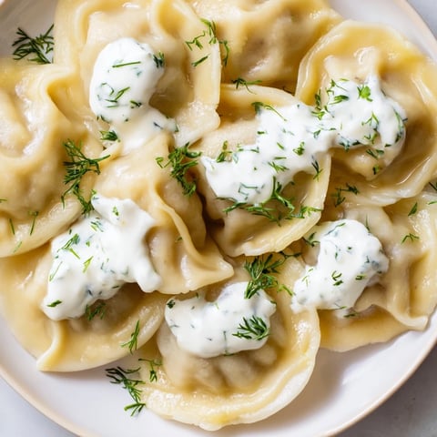 Steaming Russian Pelmeni, glistening with a creamy sour cream sauce ready to be enjoyed.
