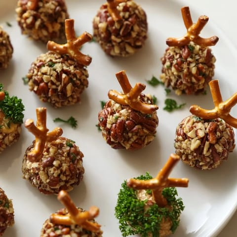 Mini acorn-shaped Acorn Cheese Ball Bites, coated in nuts and herbs, ready for serving on a platter.
