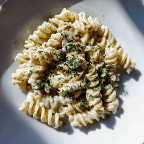 Homemade Turkish Yogurt Pasta, featuring a vibrant swirl of seasoned butter across the yogurt sauce.