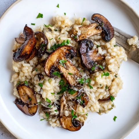 Roasted Mushroom Risotto garnished with thyme, showcasing a rich, velvety texture and savory mushroom medley.