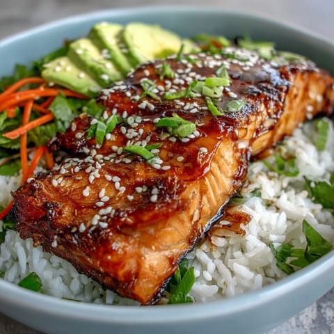 A steaming soy ginger salmon bowl features crisp veggies, fluffy rice, and ripe avocado slices.