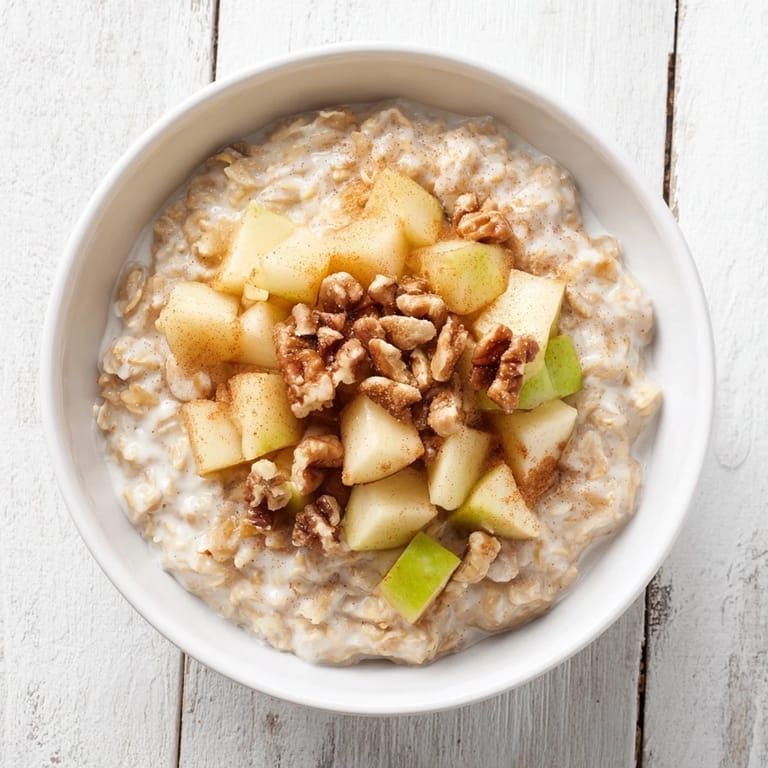 Creamy apple pie oatmeal bowl featuring tender sautéed apples, fragrant cinnamon, and toasted pecans for brunch.