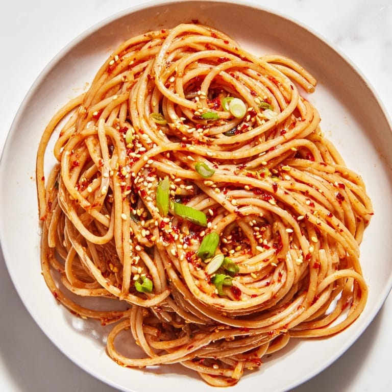 Tantalizing image of Garlic Chili Oil Noodles, perfectly coated and ready to enjoy with sesame seeds.