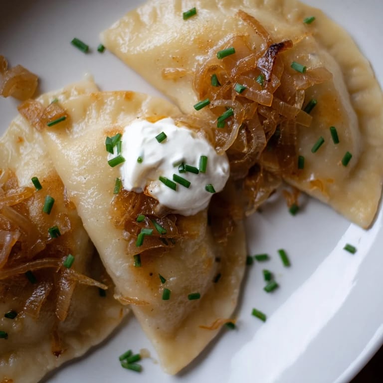 A close-up of steaming Polish pierogi, boiled then pan-fried, ready to savor with onions.