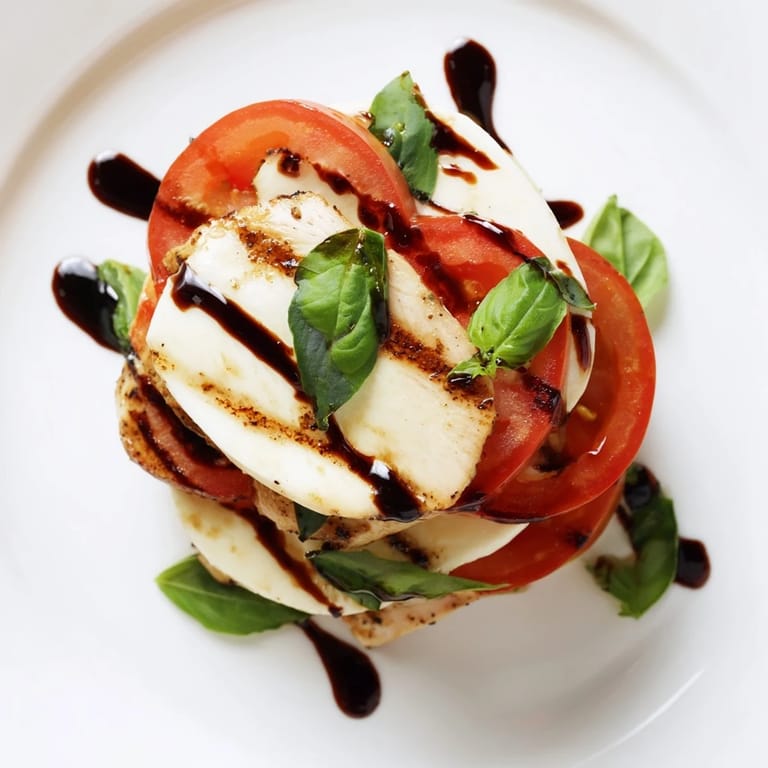 Sliced grilled chicken, juicy tomatoes, and mozzarella shine on a platter for a light meal.