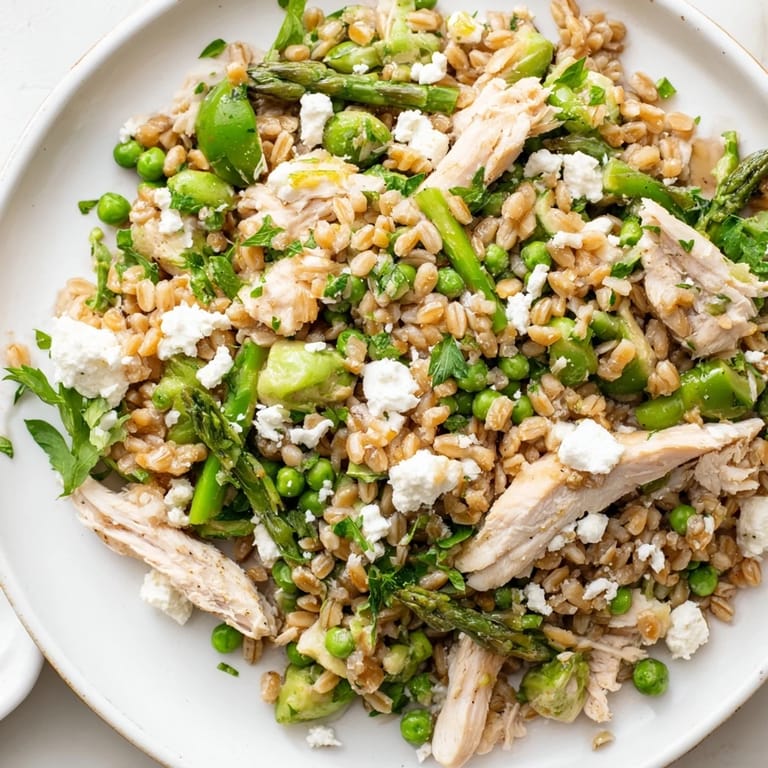 Juicy chicken and tender farro are tossed with crisp spring vegetables and arugula, garnished with crumbled feta and fresh herbs.
